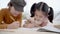 Asian Sibling having fun drawing together on bed, elder sister and adorable little girl enjoying hobby without parents in bedroom.