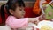 Asian sibling little girls enjoying with eating fried chicken, French fries and nectar in service shop with her family. KFC is a W