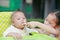 Asian sister feeding food for her little brother with love on the plastic chair