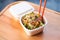 asian slaw in takeout container, chopsticks on top