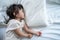 Asian sleepy baby girl daughter lying down on bed in the early morning. Adorable comfortable little kid take nap to rest and sleep