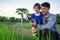 Asian smart farmer father with his happy little girl daughter using digital tablet outdoors in family organic farm