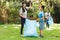 Asian son and daughter high fiving, collecting rubbish with hmother in the countryside