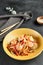 Asian Stir Fried Shrimp and Rice Noodles. Sesame Rice Noodles with Shrimp in yellow plate with wooden chopstick on dark slate