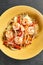 Asian Stir Fried Shrimp and Rice Noodles. Sesame Rice Noodles with Shrimp in yellow plate with wooden chopstick on dark slate