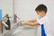 Asian student kid wearing medical face mask washing hands by himself on sink  in the basin, bathroom sink