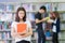 Asian student lady smile and read a book in library