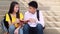 Asian Student sitting stairs at outdoor place. Couple people using book