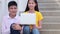 Asian Student sitting stairs at outdoor place. Couple people using book and laptop