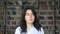 Asian student in white shirt on background of blurred bookshelves in library