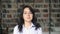 Asian student in white shirt on background of blurred bookshelves in library