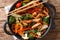 Asian style fried pork with broccoli, bok choy, carrots, peppers, cauliflower close-up in a pan. Horizontal top view