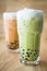 Asian style green and orange bubble tea with milk froth on top