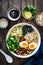 Asian style soup. Broth with chow mein noodles, boiled eggs, shiitake mushrooms, cilantro and mung sprouts on wooden table