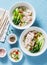 Asian style soup. Rice noodles, boiled chicken, vegetables and broth - delicious diet lunch on blue background, top view.