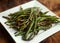 Asian style Stir fried green beans with worcester sause and sesame seeds in white square plate