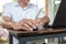 Asian tan skin holding wireless mouse on the vintage wood table and writting pencil with his left hand