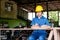 Asian technician girl with blue suit and yellow helmet use pencil to work with the wood