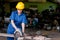 Asian technician girl with blue uniform and yellow helmet use power saw to cut some woods in workplace station