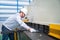 Asian technician worker wearing a safety suit and sheet Metal Shearing in industrial factory, Safety first concept