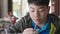 Asian teen boy drinking water from a plastic tube sitting at home