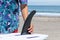 Asian Teen putting a black surfboard fin onto a white surfboard in Chiba Japan on a beach