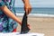 Asian Teen putting a black surfboard fin onto a white surfboard in Chiba Japan on a beach