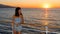 Asian teen in tube top standing on deck of ferry looking to her left at sunset