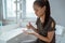 Asian teenage girl is cleaning her hands by spraying hand sanitizer while sitting