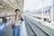 Asian teenage girl traveling using a camera take a photo to capture memories while waiting for a train at the station.