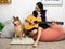 Asian teenage playing guitar with Shiba Inu dog sitting in white living room