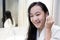 Asian teenager girl cleaning the external ear canal with a cotton swab,smiling young woman in white bathrobe,using cotton bud to