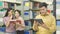 Asian teenager man reads a tablet with girls talk at the book sh