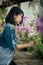 Asian teenager planting beautiful orchid flower in garden