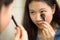 Asian teenager putting on makeup