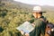 Asian teenager using compass with paoer map to hike through forest to peak of mountain