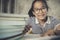 Asian teenager wearing eye glasses doing home work with stack of