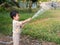 Asian Thai cute child boy holding water hose with water splash.