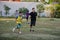 Asian thai father training and playing football or soccer with son at playground on yard in public garden park in Thailand