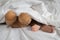 Asian toddler feet beside teddy bear feet in white bed, sheet and pillow