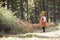 Asian toddler girl walking alone in a forest, side view
