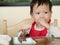 Asian toddler learn to eat meal herself.