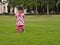 Asian toddler is learning to walk step by step on greeny grass.