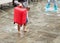 Asian tourist barefoot in the water with her luggage. Venice, It