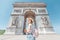 Asian tourist girl enjoys the view of the majestic and famous Arc de Triomphe or Triumphal arch. Follow me and Travel to
