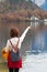 Asian tourist traveler girl from back standing pointing finger at Hallstatt lake Austria in autumn; freedom peaceful relax