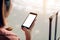 Asian tourist woman hands holding and using smartphone with blank screen waiting for flight in airport lounge