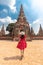 Asian tourist woman in red dress and sun hat from back view, walking through the beautiful history castle and historic temple