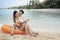 Asian traveller couple sitting and see sunset togather on the beach with longtail boat background