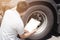 Asian a truck driver holding clipboard inspecting safety check a truck wheels and tires.